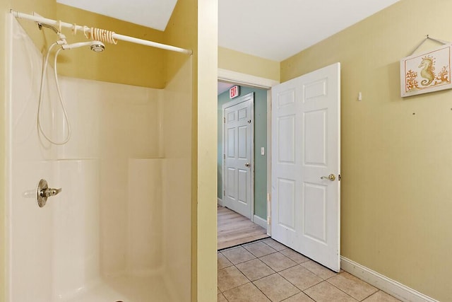 bathroom featuring walk in shower, tile patterned floors, and baseboards