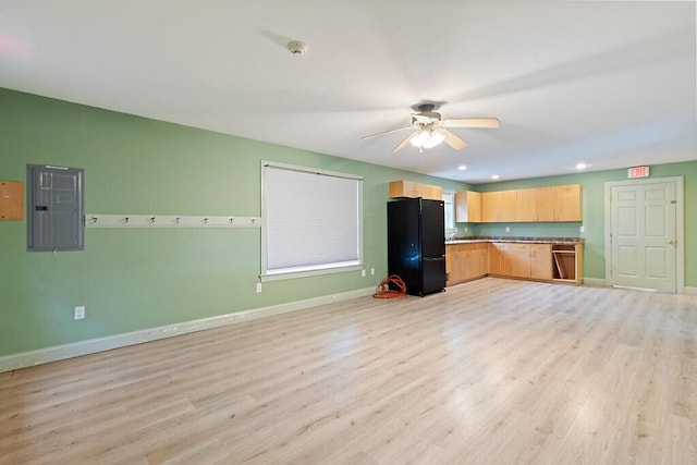 kitchen with light brown cabinets, light wood-style flooring, freestanding refrigerator, electric panel, and a ceiling fan