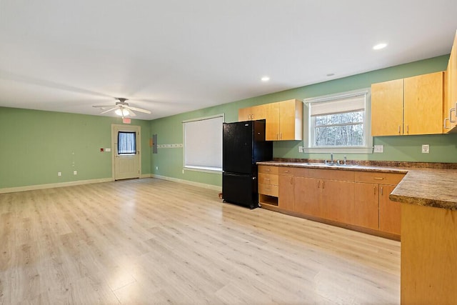 kitchen featuring light wood-style floors, ceiling fan, freestanding refrigerator, and a sink