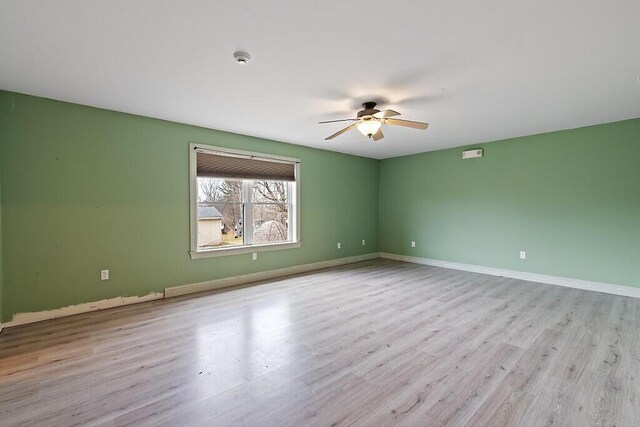 empty room featuring baseboards, wood finished floors, and ceiling fan