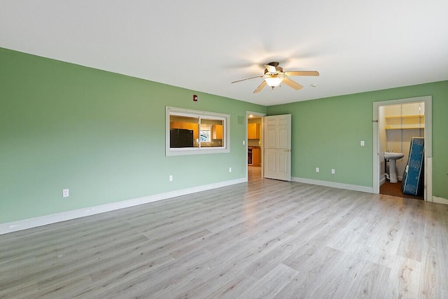 unfurnished bedroom with fridge, baseboards, wood finished floors, and a spacious closet