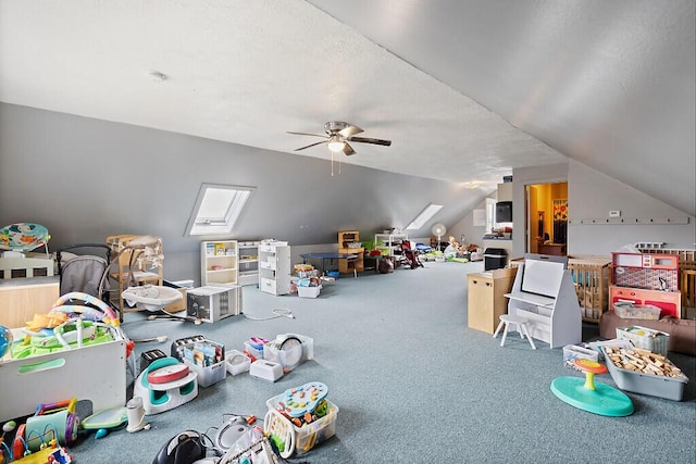game room with a ceiling fan, vaulted ceiling with skylight, and carpet flooring