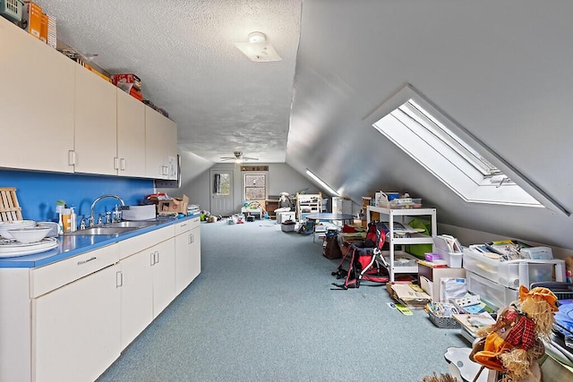interior space featuring carpet floors, ceiling fan, a sink, open floor plan, and lofted ceiling with skylight