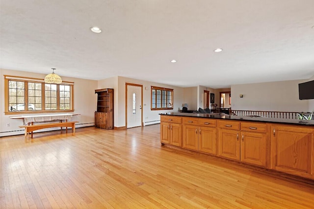 kitchen with a baseboard radiator, dark countertops, light wood-style flooring, and a baseboard heating unit