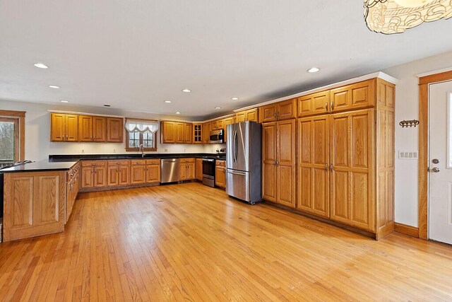 kitchen featuring recessed lighting, dark countertops, light wood-style floors, and appliances with stainless steel finishes