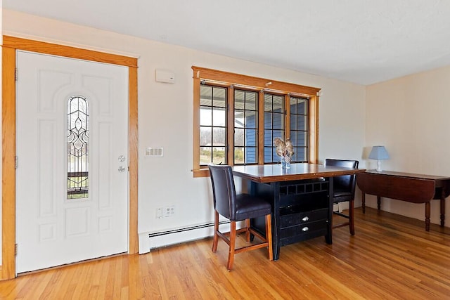 dining space featuring wood finished floors and a baseboard heating unit
