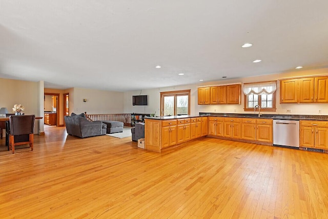 kitchen with light wood finished floors, dishwasher, dark countertops, and a healthy amount of sunlight