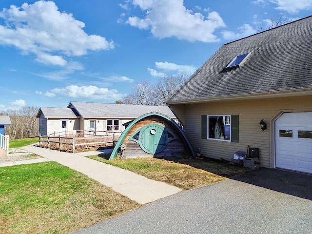 view of front of property featuring aphalt driveway, a shingled roof, and a garage