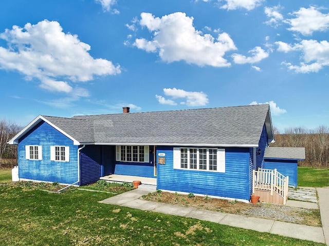 ranch-style home featuring a front yard, a shingled roof, covered porch, and a chimney