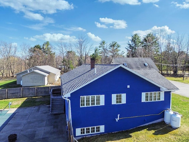view of side of property with a chimney, a patio area, fence, stairway, and a yard