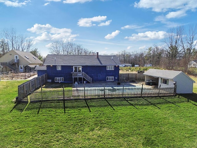 rear view of house with an outbuilding, stairs, a yard, and a fenced backyard