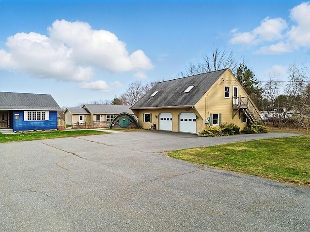 view of front of home with a front lawn, stairs, a garage, and aphalt driveway