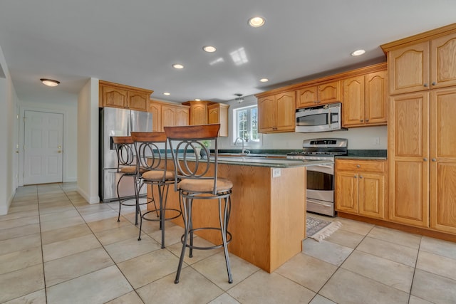 kitchen with a kitchen breakfast bar, light tile patterned floors, appliances with stainless steel finishes, a center island, and recessed lighting