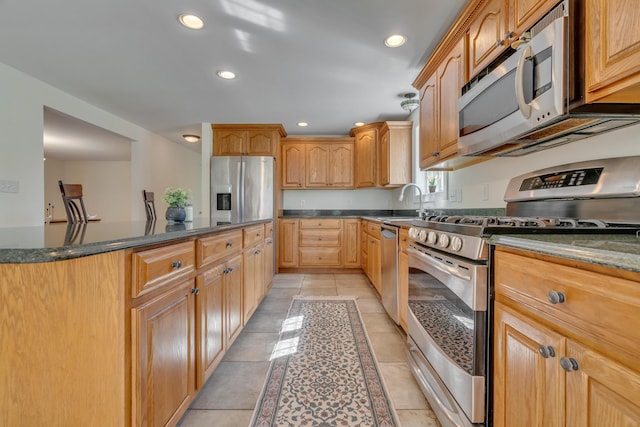 kitchen with recessed lighting, light tile patterned flooring, dark stone countertops, and stainless steel appliances