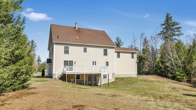 back of house featuring a deck, a yard, and roof with shingles