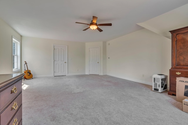 unfurnished living room featuring light colored carpet, a ceiling fan, and baseboards
