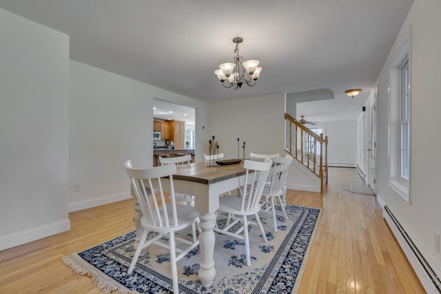 dining room featuring an inviting chandelier, stairway, light wood finished floors, and baseboard heating