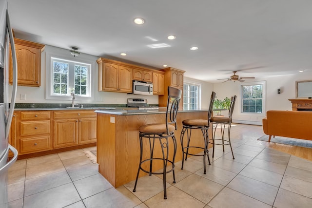 kitchen featuring appliances with stainless steel finishes, a breakfast bar, a healthy amount of sunlight, and recessed lighting