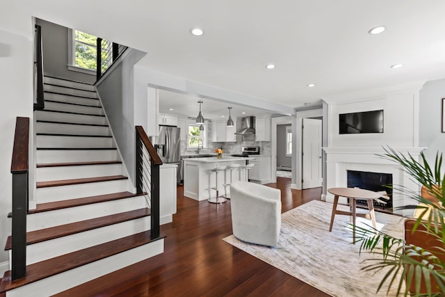 living room featuring a fireplace, recessed lighting, stairway, and dark wood-type flooring