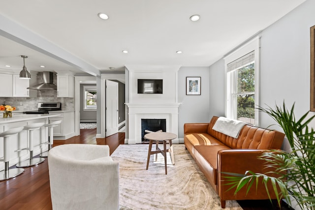 living area with a large fireplace, recessed lighting, and dark wood-style floors