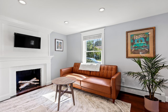 living area with recessed lighting, wood finished floors, a baseboard heating unit, baseboards, and a fireplace with flush hearth
