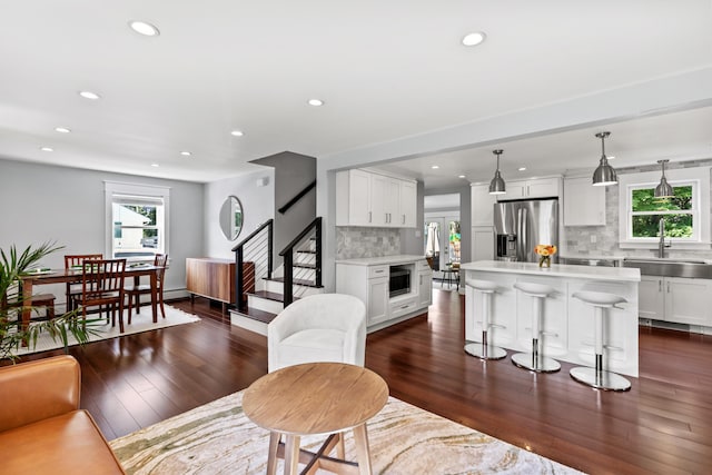 living area with recessed lighting, baseboards, dark wood finished floors, and stairs
