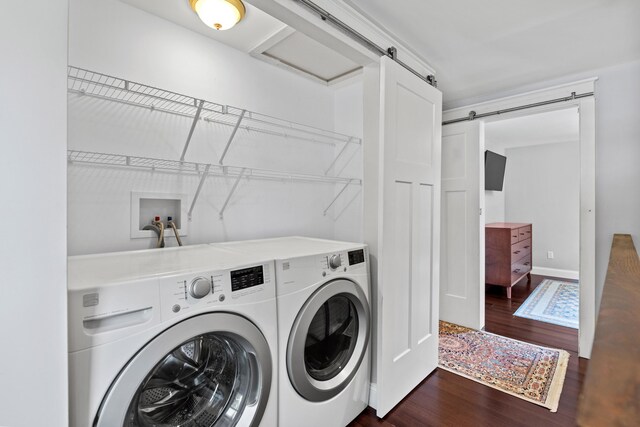 washroom with dark wood-style floors, a barn door, separate washer and dryer, and laundry area