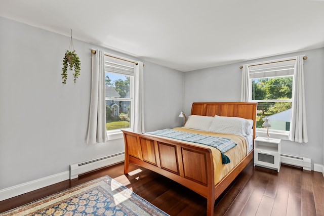 bedroom featuring dark wood-style flooring, a baseboard heating unit, and multiple windows