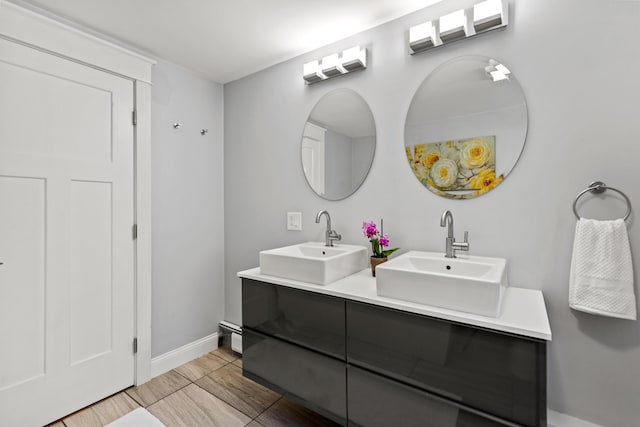 full bathroom with baseboards, double vanity, and a sink