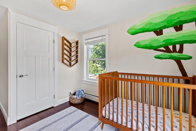 bedroom featuring wood finished floors, baseboard heating, and baseboards