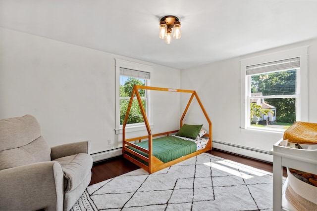 bedroom featuring multiple windows, baseboard heating, and wood finished floors