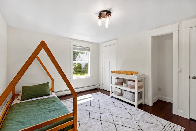 bedroom with baseboards, baseboard heating, wood finished floors, and a baseboard radiator