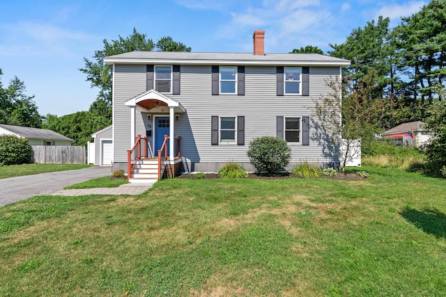 view of front of home featuring a front yard, an outdoor structure, a detached garage, a chimney, and fence