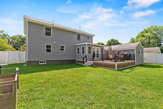 rear view of property featuring a fenced backyard, a gate, a wooden deck, a sunroom, and a lawn