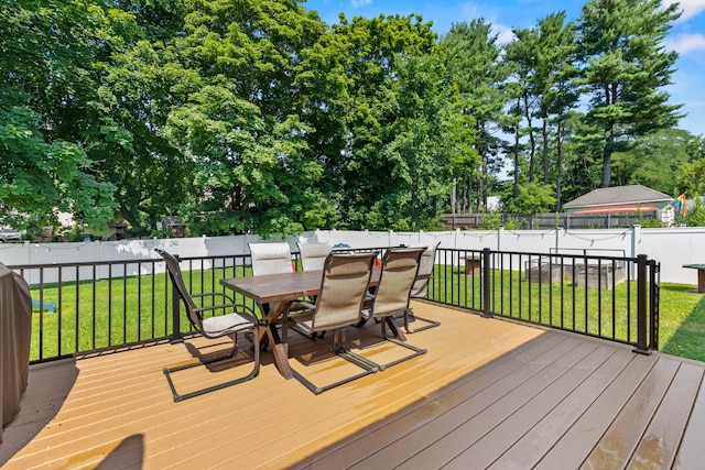 wooden terrace with outdoor dining space, a fenced backyard, and a yard