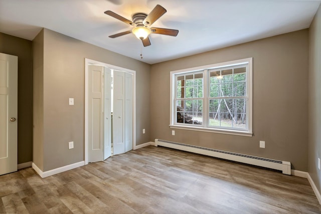 unfurnished bedroom featuring wood finished floors, baseboard heating, and baseboards