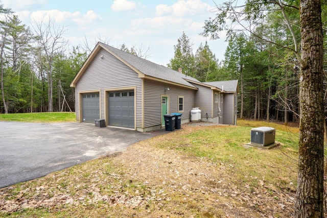 view of side of home featuring a lawn, roof with shingles, and a garage
