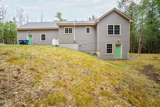 back of property with a yard and a shingled roof