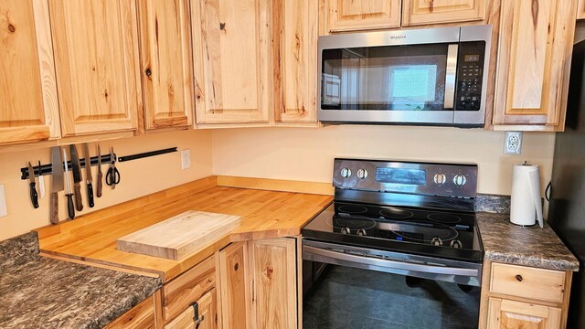 kitchen featuring electric stove, light brown cabinetry, and stainless steel microwave