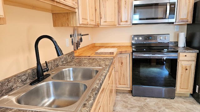 kitchen with light brown cabinetry, a sink, and appliances with stainless steel finishes