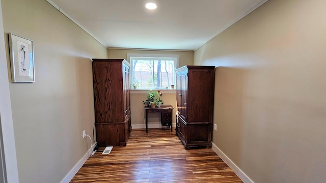 hallway featuring baseboards, dark wood-style flooring, and crown molding