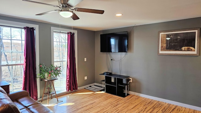 living area with recessed lighting, wood finished floors, ornamental molding, ceiling fan, and baseboards