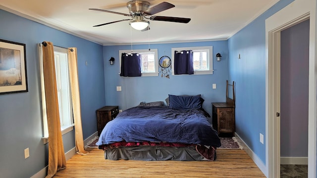 bedroom with ornamental molding, ceiling fan, wood finished floors, and baseboards