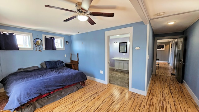 bedroom featuring baseboards, wood finished floors, a ceiling fan, and ensuite bathroom
