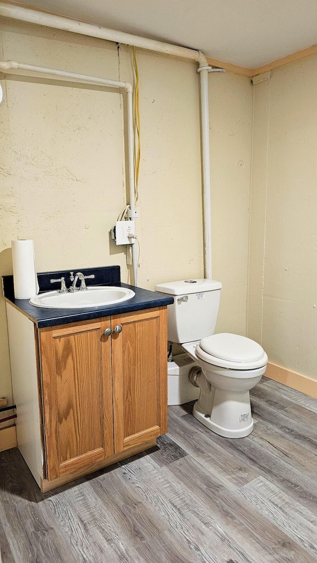 bathroom featuring baseboards, wood finished floors, toilet, and vanity