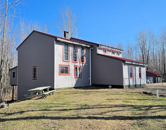 rear view of house with a chimney and a yard