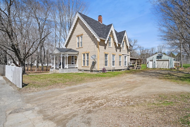 126 Elm St, Newport, ME 04953 - view of side of property featuring a porch, an outdoor structure, a chimney, a detached garage, and roof with shingles
