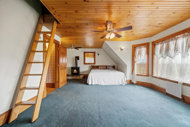 bedroom featuring wood ceiling, a wood stove, baseboards, carpet floors, and radiator heating unit