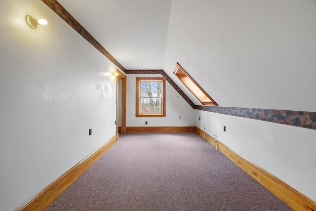 additional living space featuring baseboards, wood finished floors, and lofted ceiling with skylight