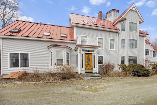 view of front of property with a standing seam roof, a chimney, and metal roof